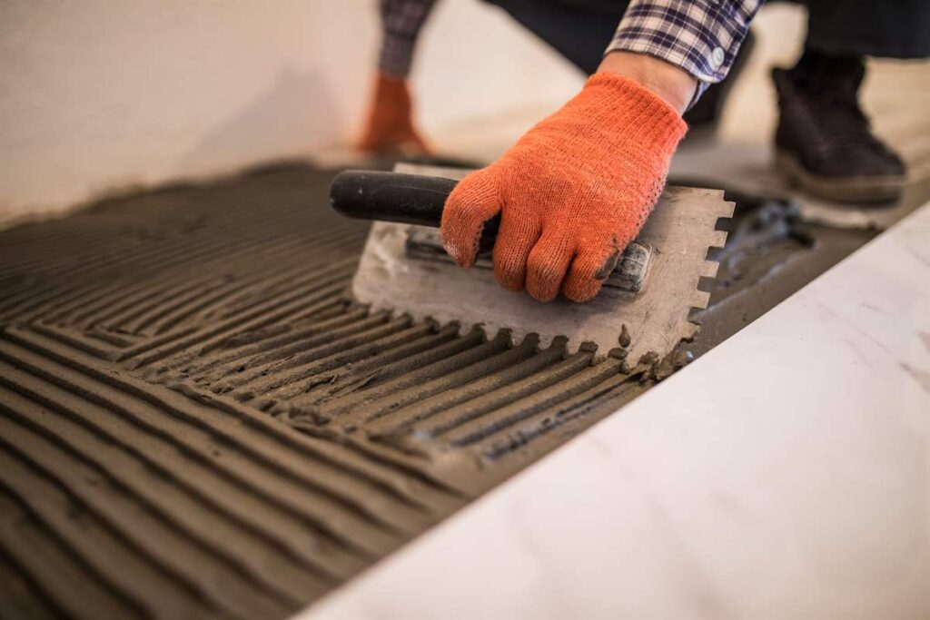 Laying Cermainc Tile Trowelling onto concrete floor preparation for white floor tile